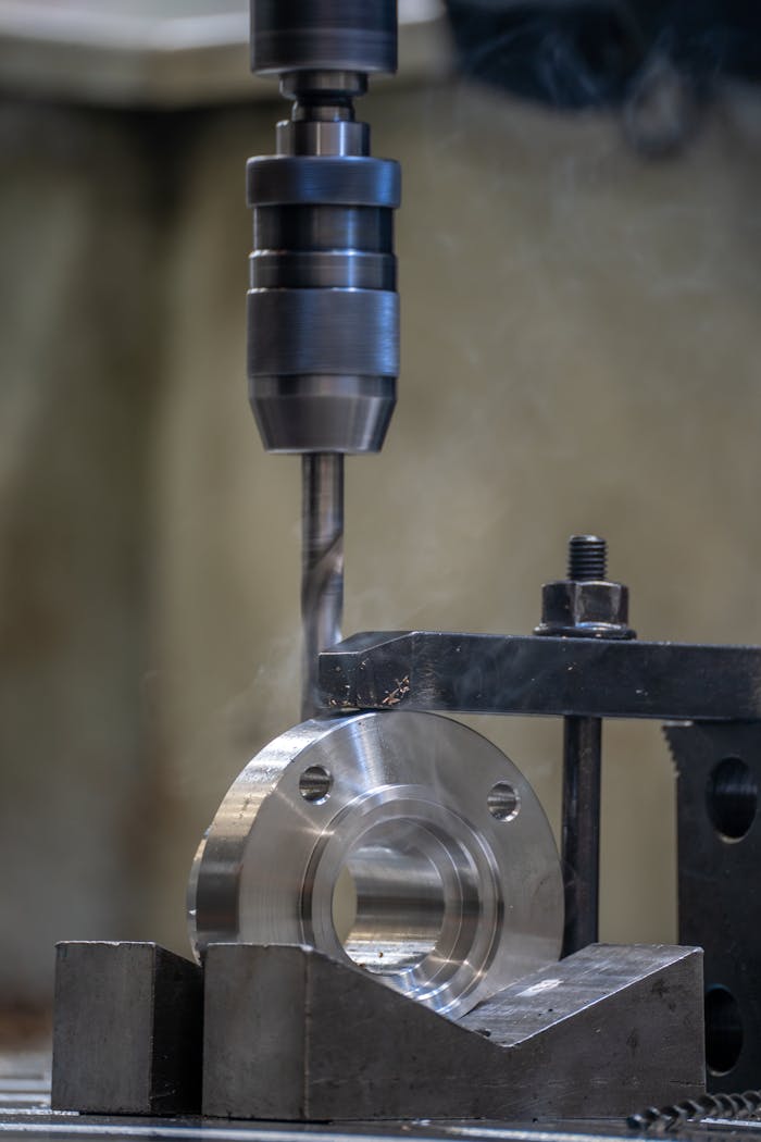 services-02 Close-up view of a metal drilling process in an industrial workshop setting.